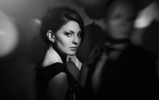 A woman in dark evening wear looking over her shoulder in dim, moody light.