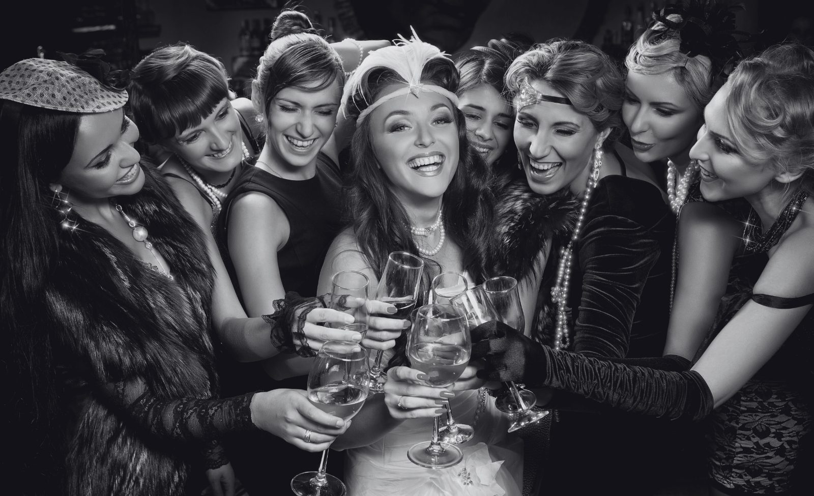Guests in 1920s dresses and headbands toasting with champagne at a party.
