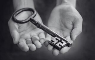 2 open hands holding a large antique key.