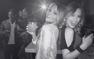 Friends laughing together with drinks in their hands at a party.