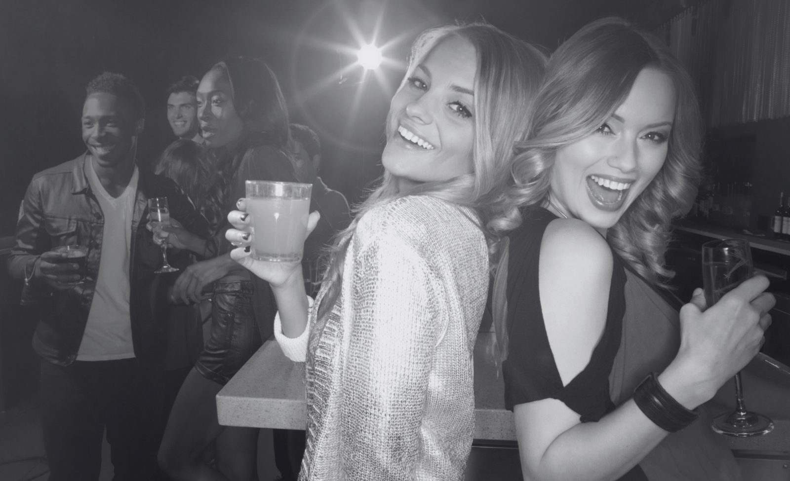 Friends laughing together with drinks in their hands at a party.