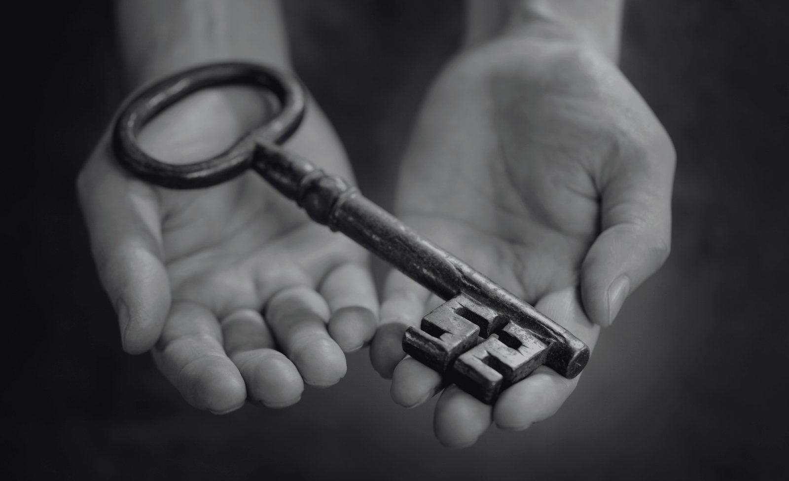 87-opt 2 open hands holding a large antique key.