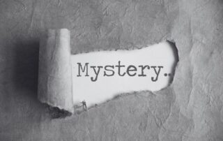 Torn paper revealing the handwritten word Mystery underneath.