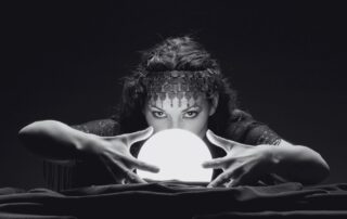 A fortune teller leaning over a glowing crystal ball.