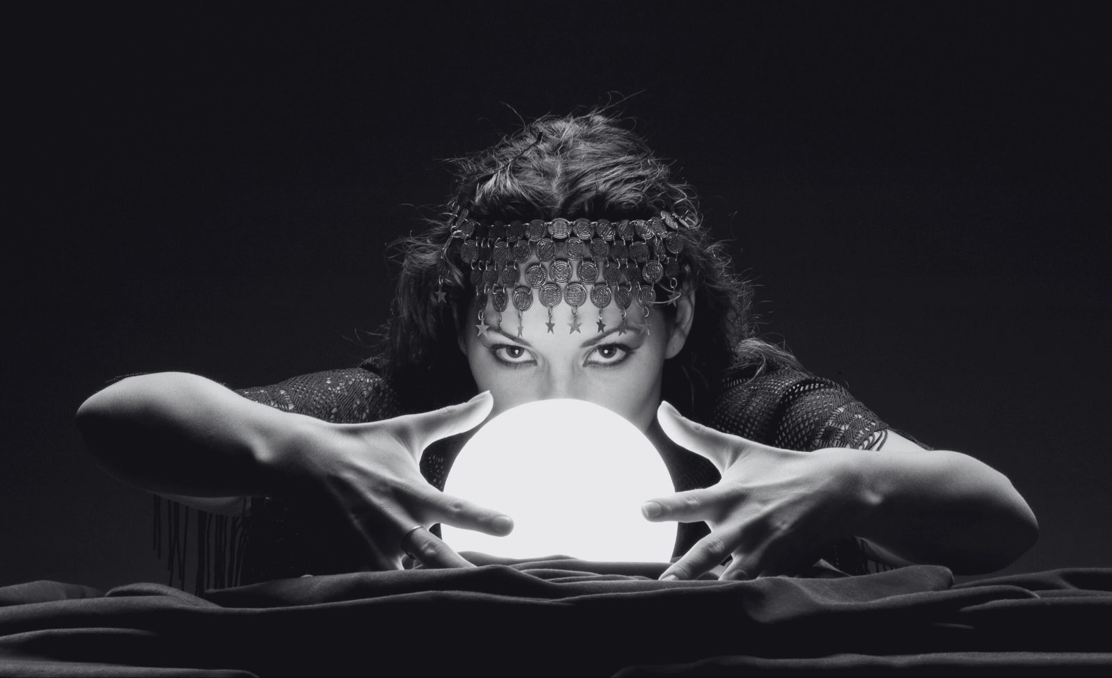 90-2-opt A fortune teller leaning over a glowing crystal ball.