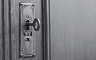 An old key left in the keyhole of a wooden door.