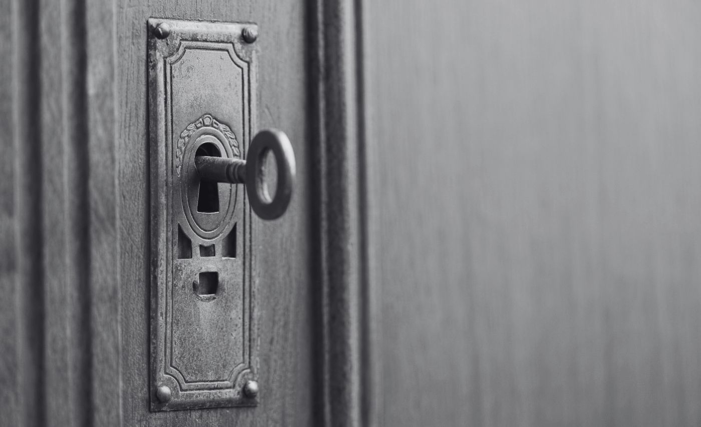 An old key left in the keyhole of a wooden door.