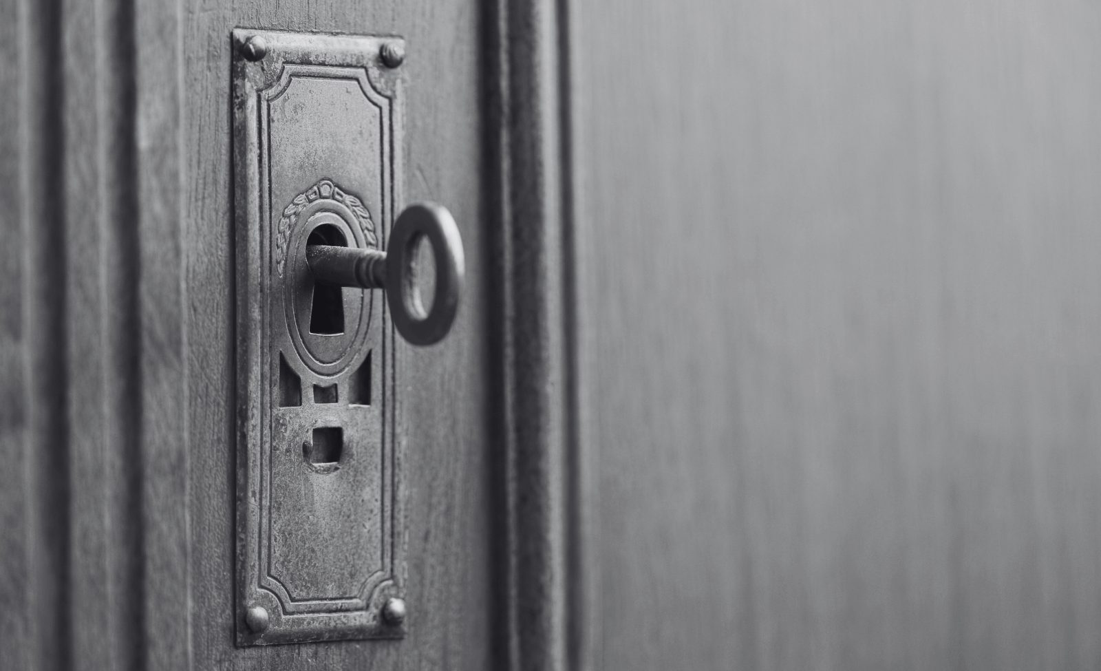 90-3-opt An old key left in the keyhole of a wooden door.