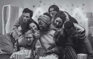 A group of friends laughing and leaning on each other on a sofa.
