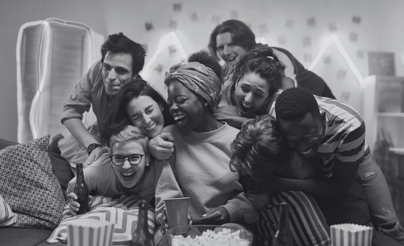 A group of friends laughing and leaning on each other on a sofa.
