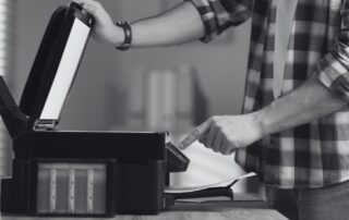 Hands feeding paper into a home printer.