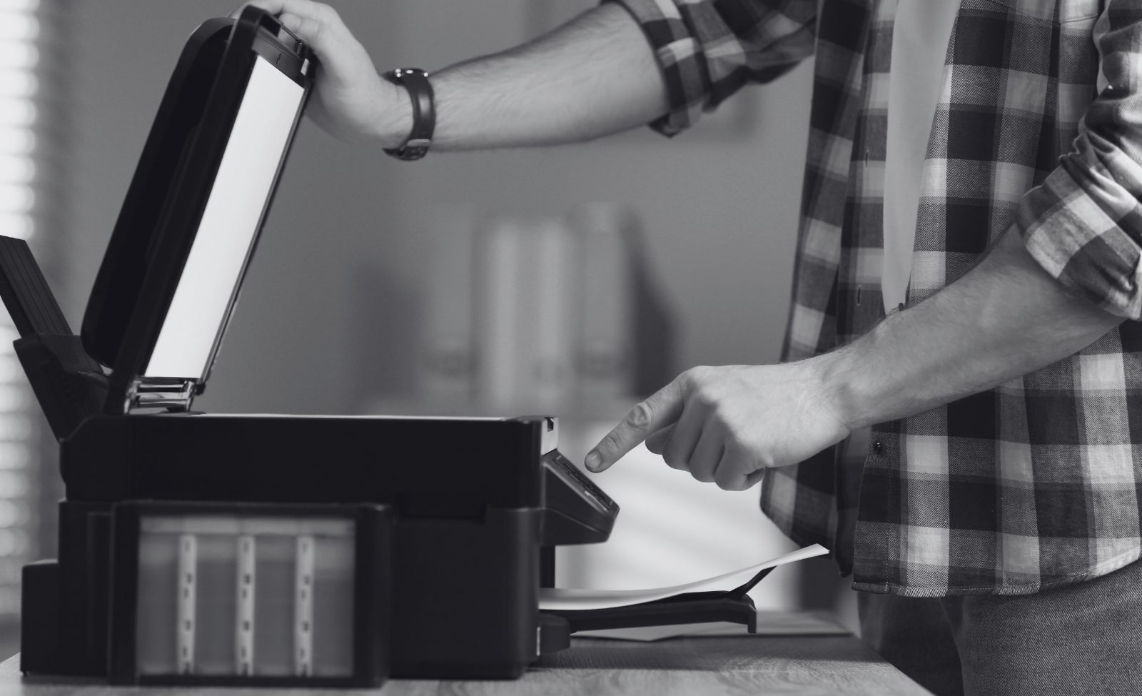 Hands feeding paper into a home printer.