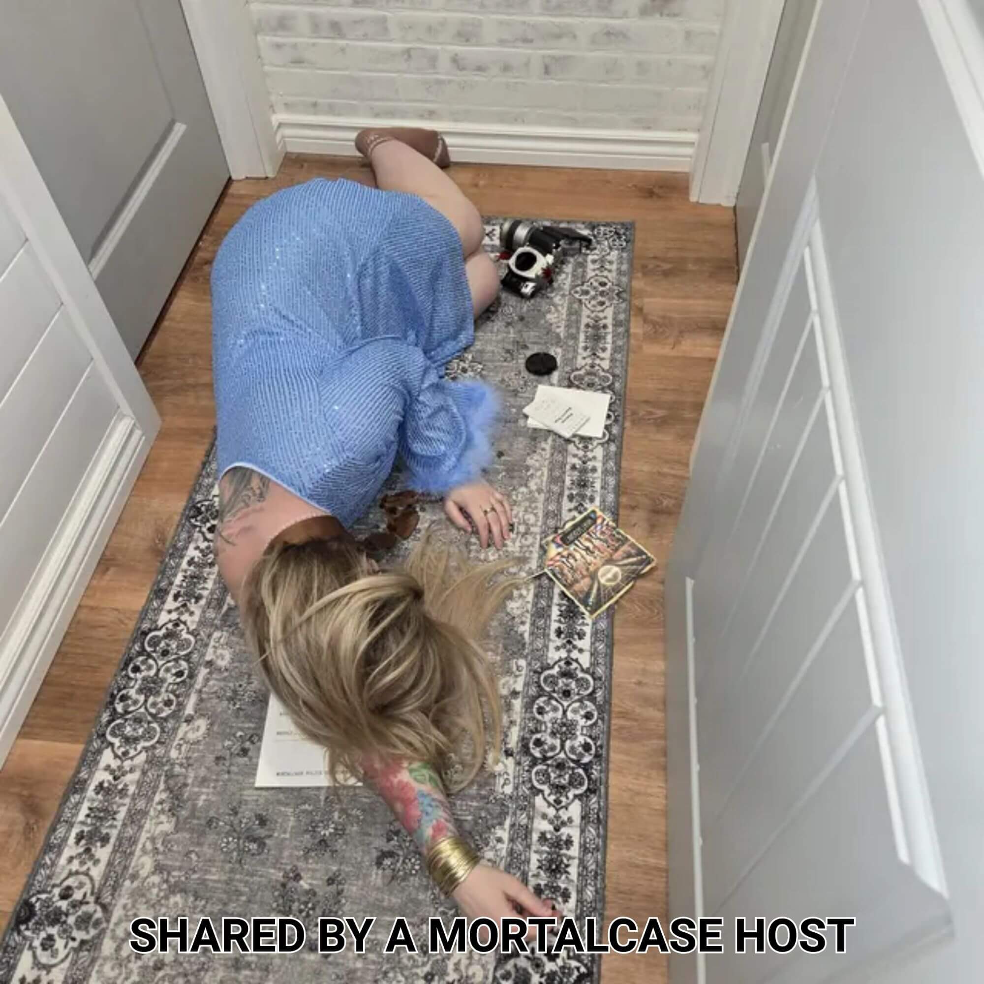 Guest posing as a murder victim beside printed clues and a camera during A Killer Disco Party.